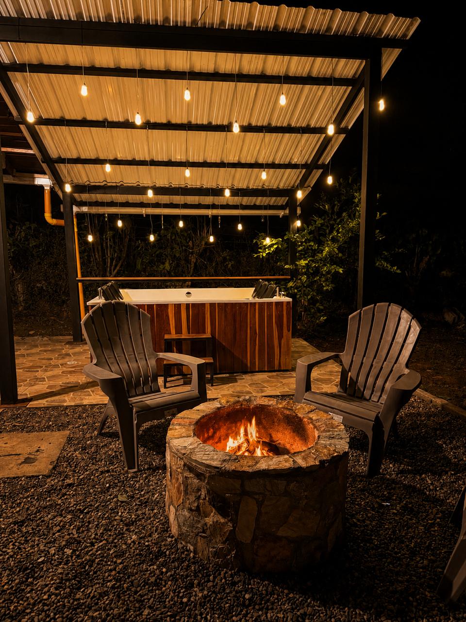 Fogata encendida y jacuzzi bajo la pérgola de noche