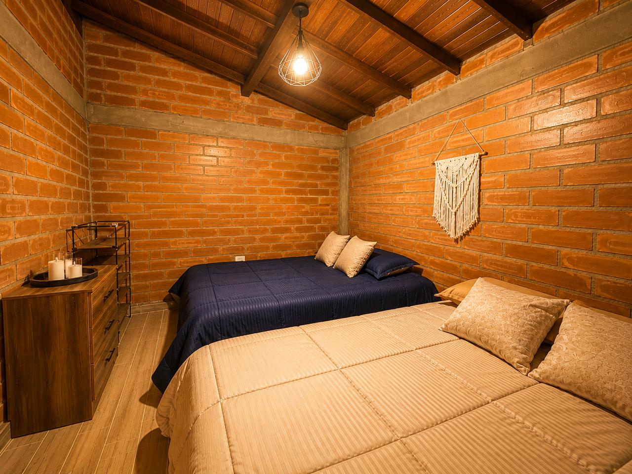 Habitación con dos camas y muro de ladrillo